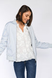 Model kombiniert weiße Bluse mit 3D-Bluetenstickerei mit blauem Blouson und Jeans.