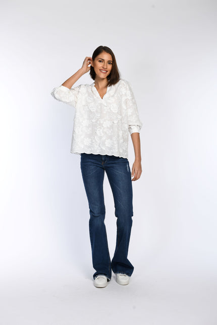 Model trägt weiße Bluse mit floraler 3D-Stickerei.