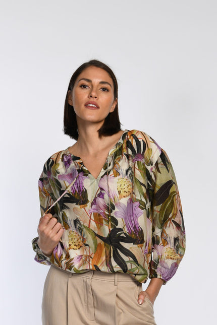 Model trägt leicht fallende Bluse mit floralem Druck und Rundhalsausschnitt mit Bindebändern. 