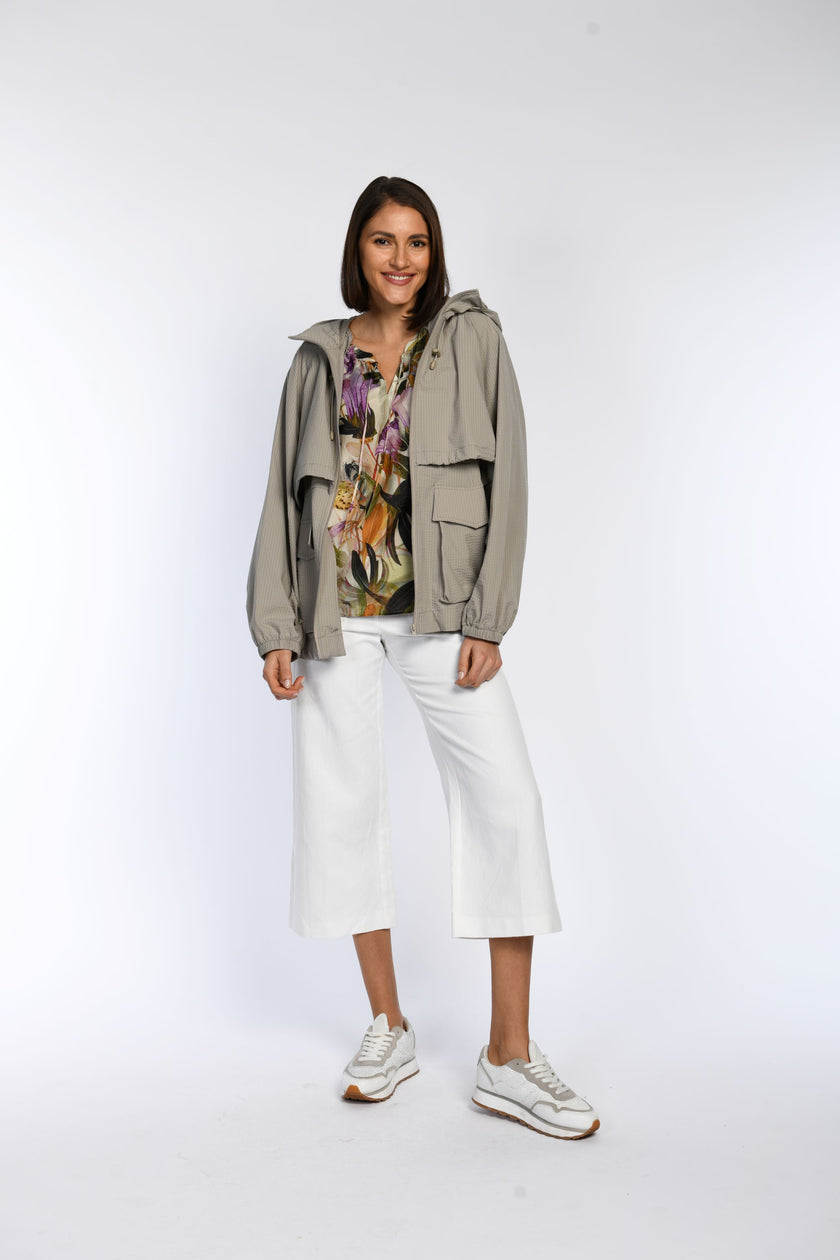 Model trägt leicht fallende Bluse, kombiniert mit taupefarbener Jacke und weißer Jeans.