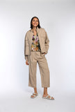 Model trägt Bluse mit floralem Druck, kombiniert mit beiger Hose und Blouson.