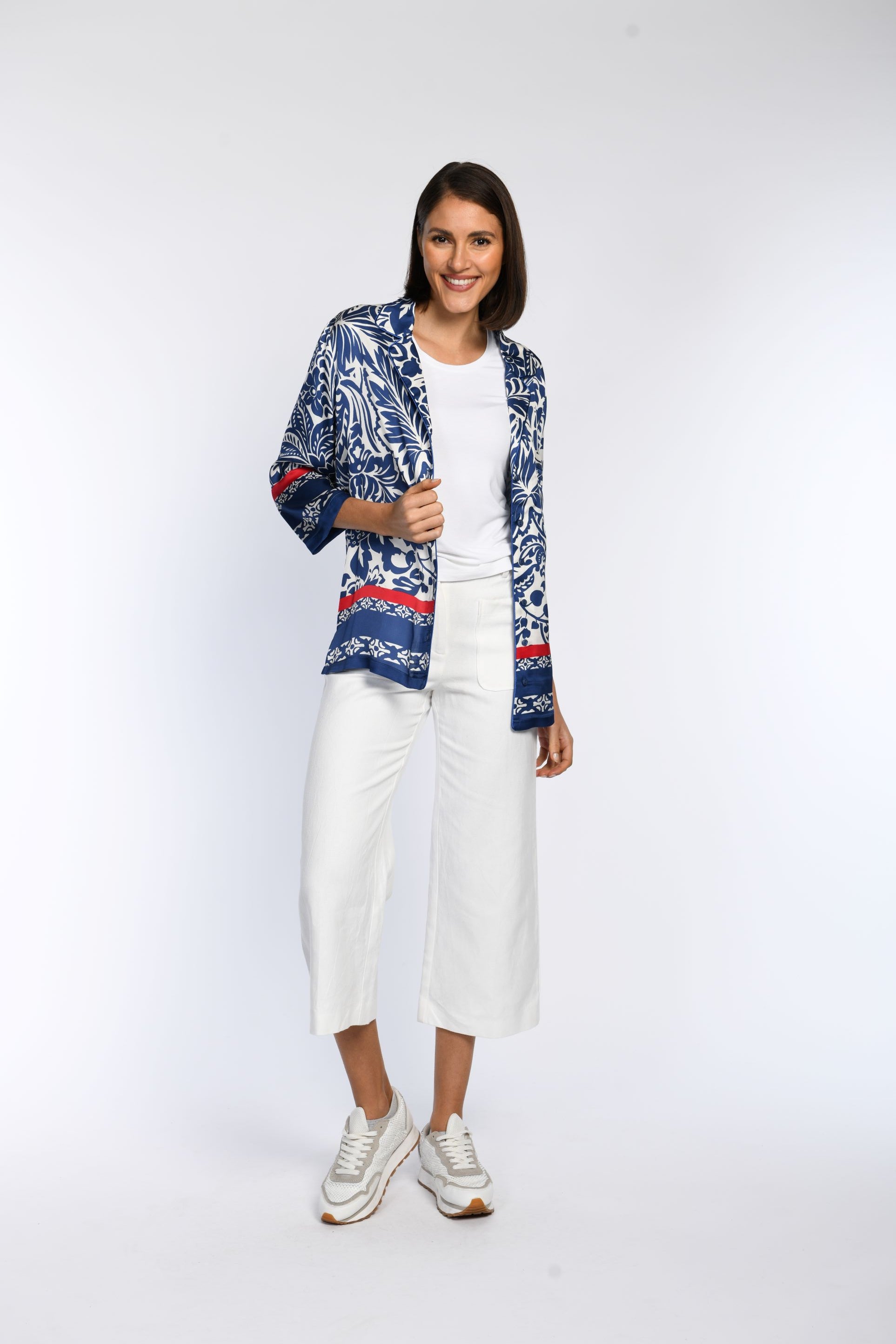 Model präsentiert eine blau bedruckte Bluse mit roten Akzenten und 3/4-Ärmeln. 