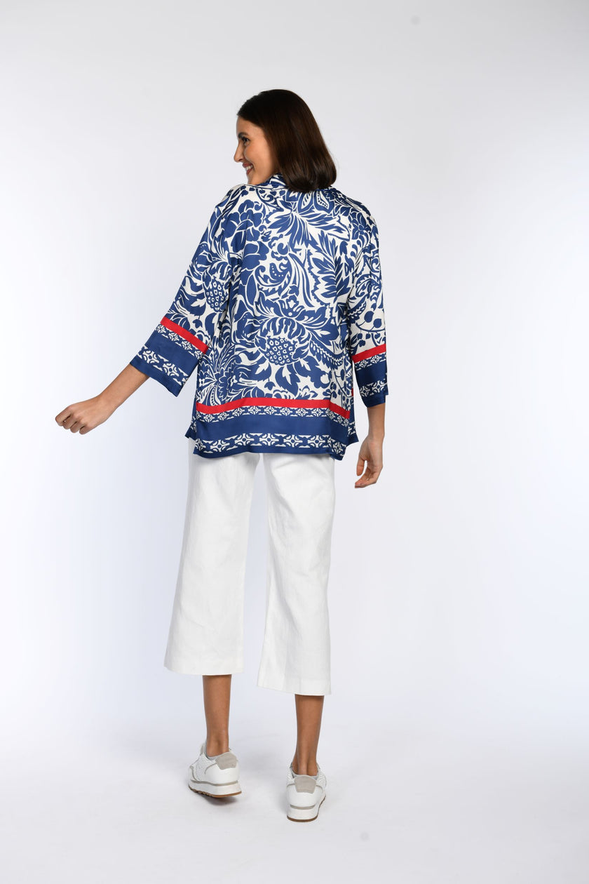 Rückenansicht einer blauen, bedruckten Bluse mit roten Akzenten.