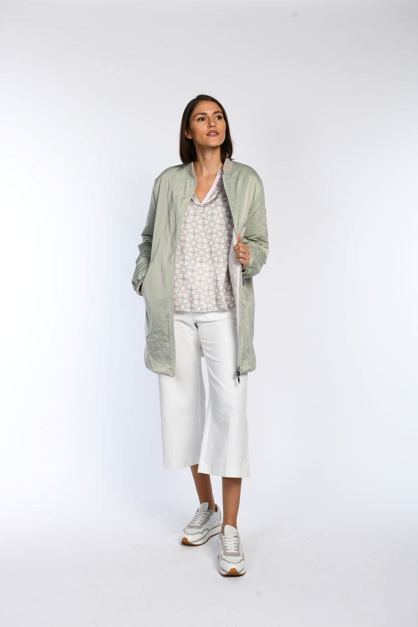 Model trägt eine Tunikabluse mit Pastelldruck, kombiniert mit einem langen Wendeblouson.