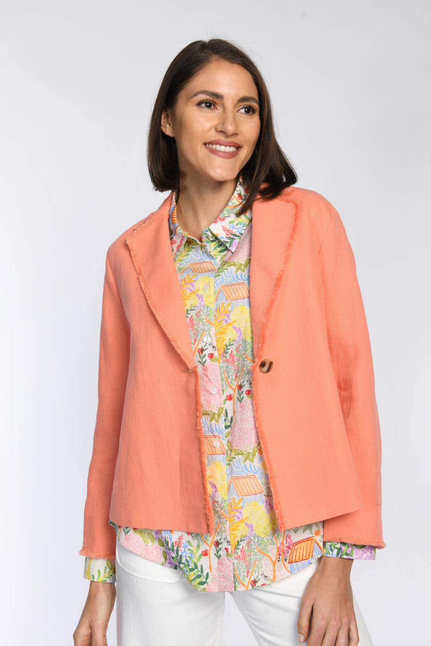 Hembluse mit fröhlichem Allover-Print, die unter einer orangefarbenen Kastenjacke getragen wird. 
