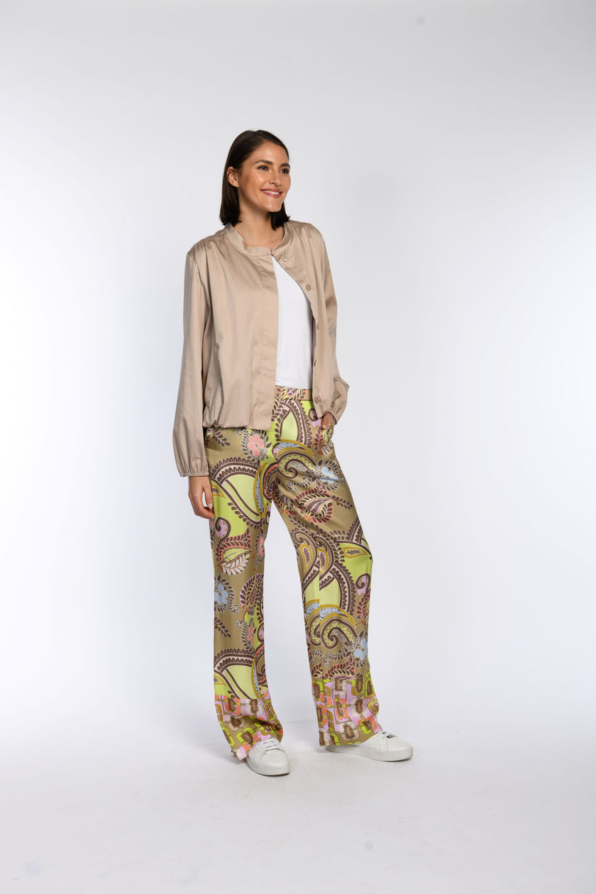 Model trägt eine weite Hose aus bedruckter Viskose, kombiniert mit einem taupefarbenen Blouson.