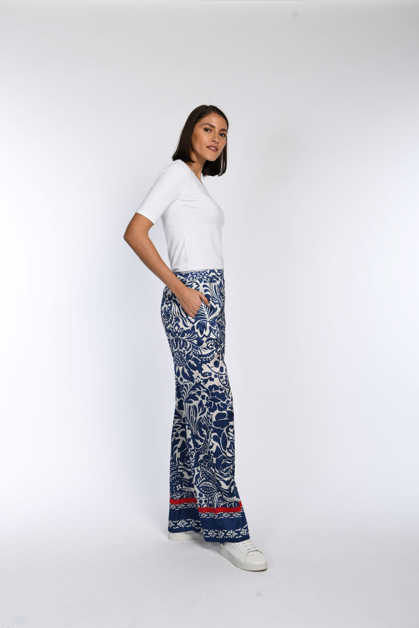 Model trägt eine weite Hose mit Bordürendruck am Hosensaum und seitlichen Taschen.