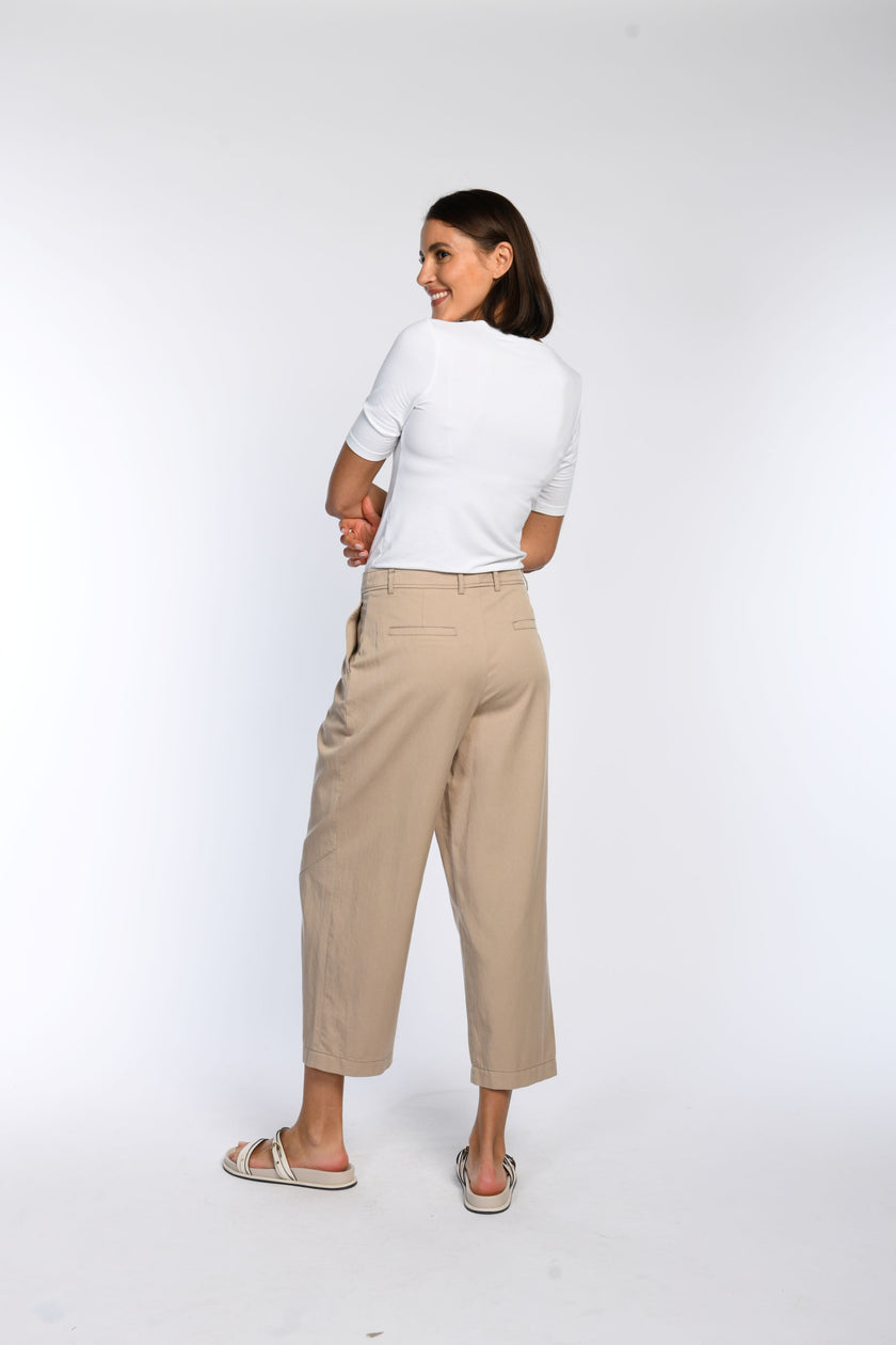 Verkürzte beige Hose mit weitem Bein, Gürtelschlaufen und Leistentaschen im Rückteil.
