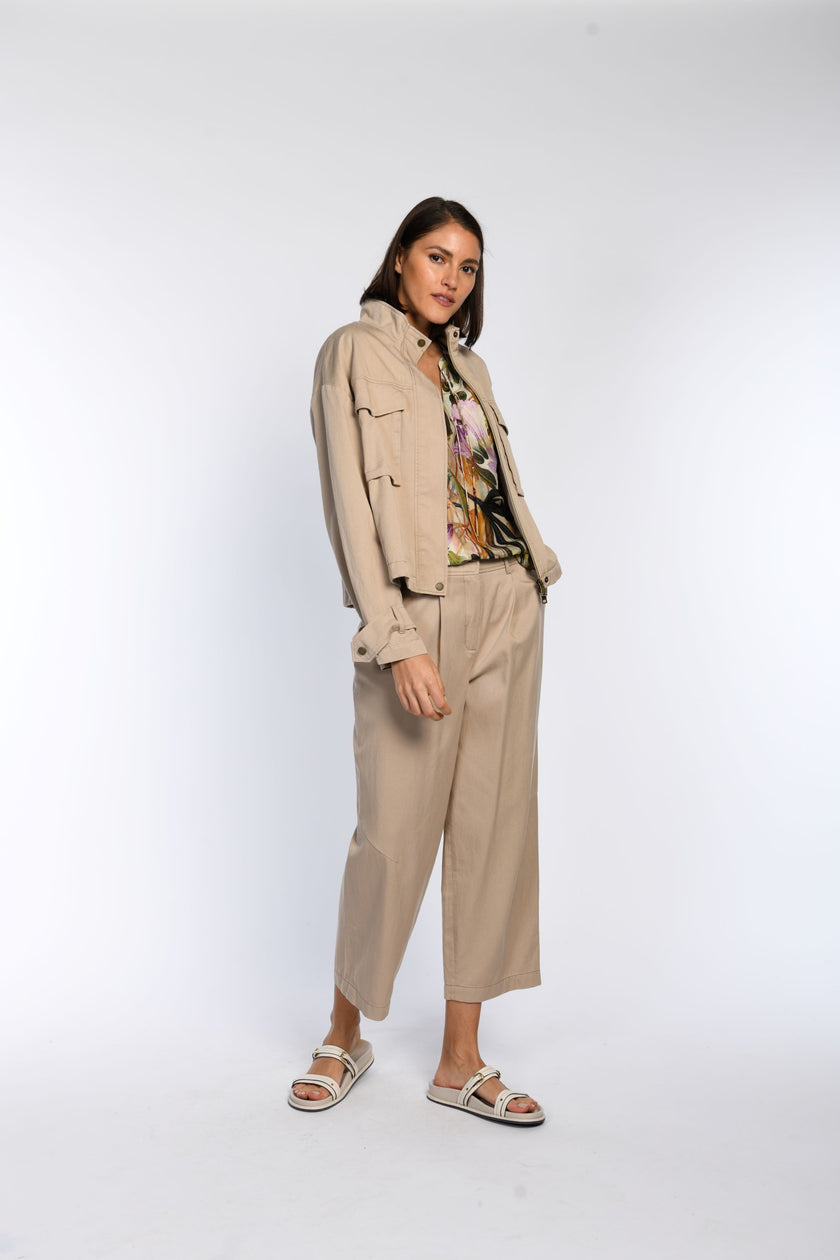 Model trägt ein Set aus locker geschnittener Hose mit Bundfalten und Blouson mit Stehkragen und Brusttaschen.