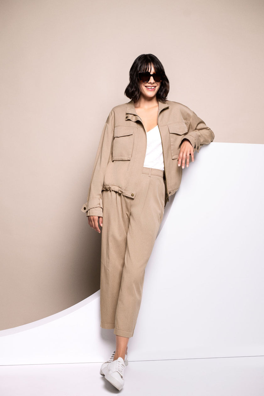Model trägt ein Set aus verkürzter Hose in Beige und sportivem Blouson.