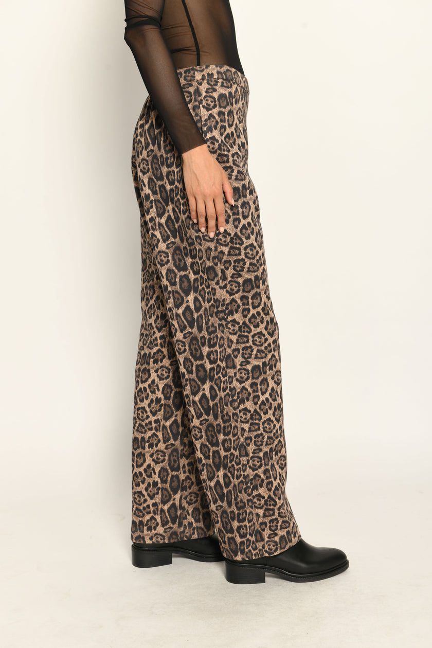 Lange Hose aus Scuba im Leo-Dessin für Damen, lässig kombiniert mit schwarzem transparentem Oberteil – Seitenansicht.