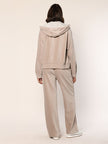 Model trägt eine  lässig sitzende Cord Hose aus Baumwoll Jersey in der Farbe Beige  - Rückansicht.