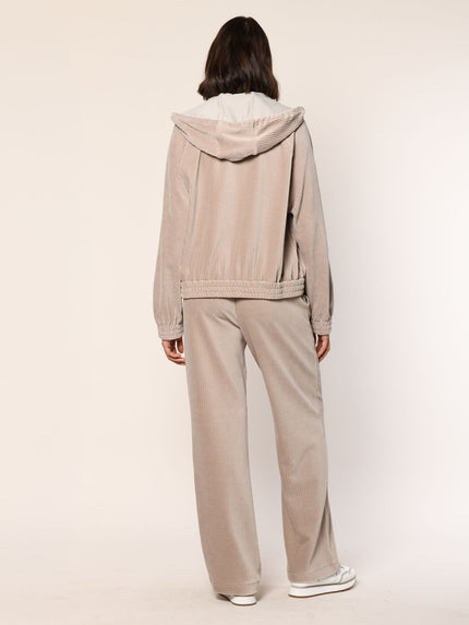Model trägt eine  lässig sitzende Cord Hose aus Baumwoll Jersey in der Farbe Beige  - Rückansicht.
