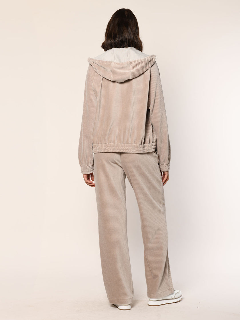 Model trägt eine  lässig sitzende Cord Hose aus Baumwoll Jersey in der Farbe Beige  - Rückansicht.