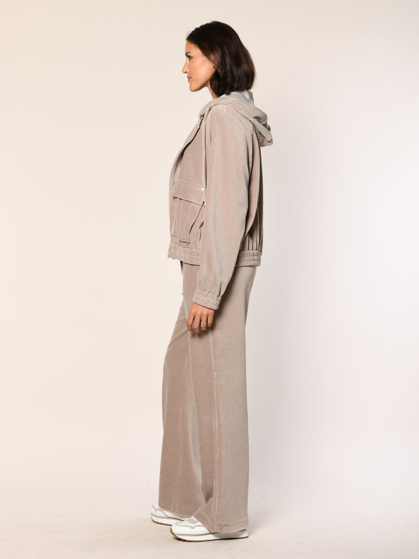 Model trägt eine  lässig sitzende Cord Hose aus Baumwoll Jersey in der Farbe Beige  - Seitenansicht.