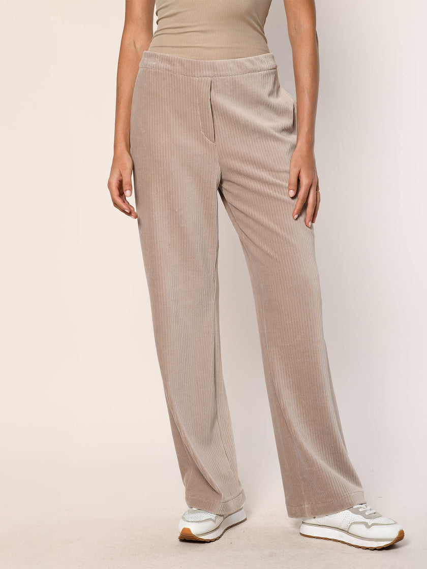 Model trägt eine  lässig sitzende Cord Hose aus Baumwoll Jersey in der Farbe Beige  - Vorderansicht Hose