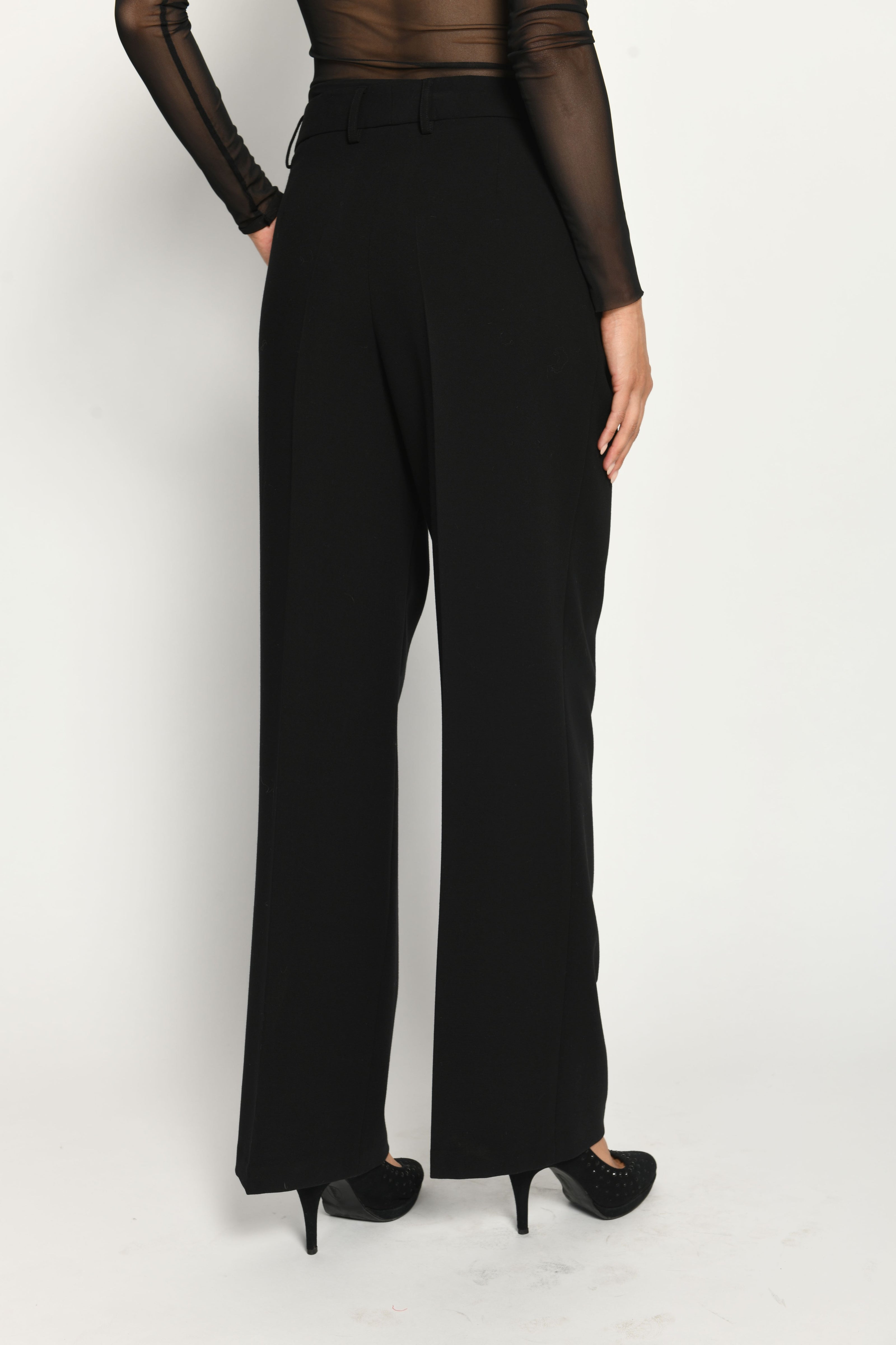 Lange Anzughose für Damen in der Farbe Schwarz, lässig kombiniert mit schwarzem transparentem Oberteil – Rückansicht.