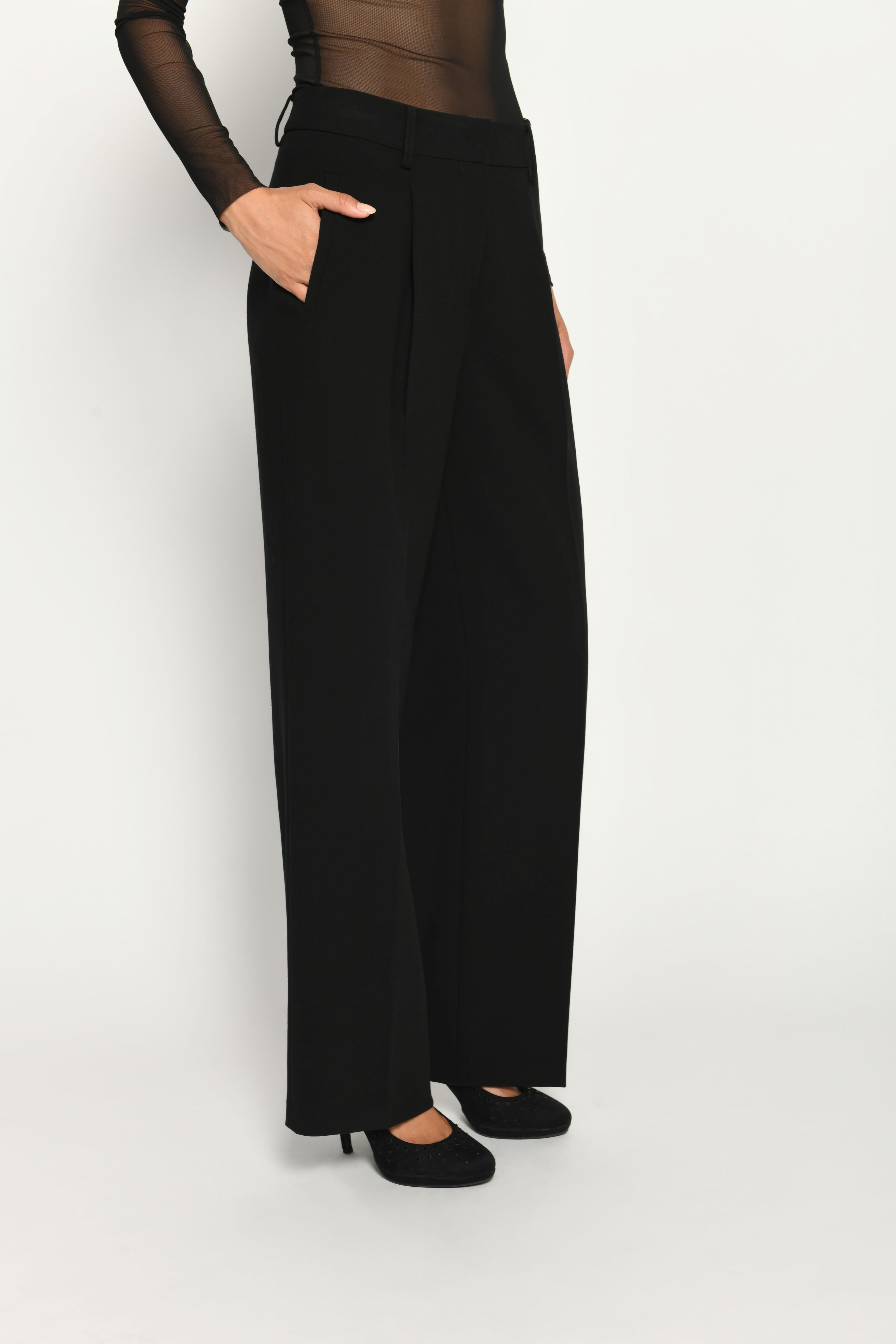 Lange Anzughose für Damen in der Farbe Schwarz, lässig kombiniert mit schwarzem transparentem Oberteil – Seitenansicht.