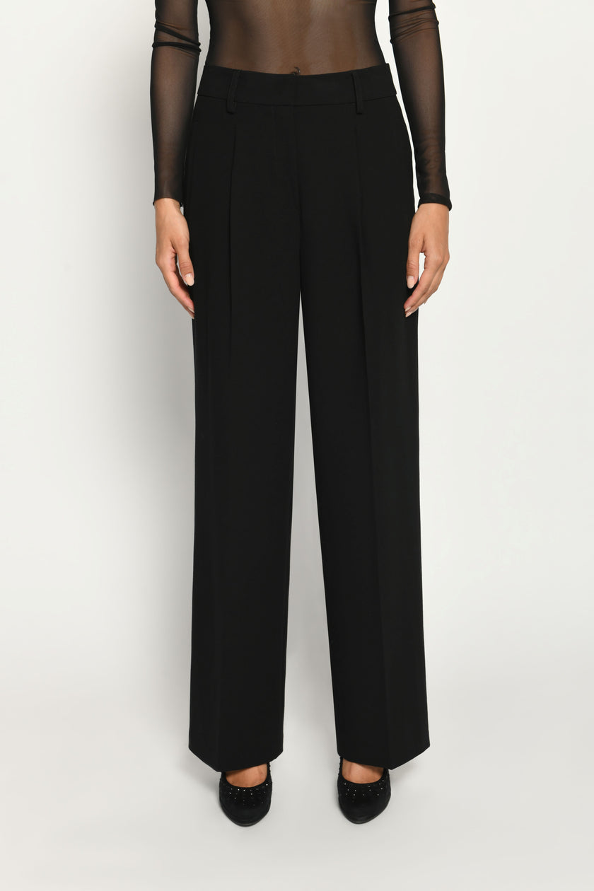 Lange Anzughose für Damen in der Farbe Schwarz, lässig kombiniert mit schwarzem transparentem Oberteil – Vorderansicht.