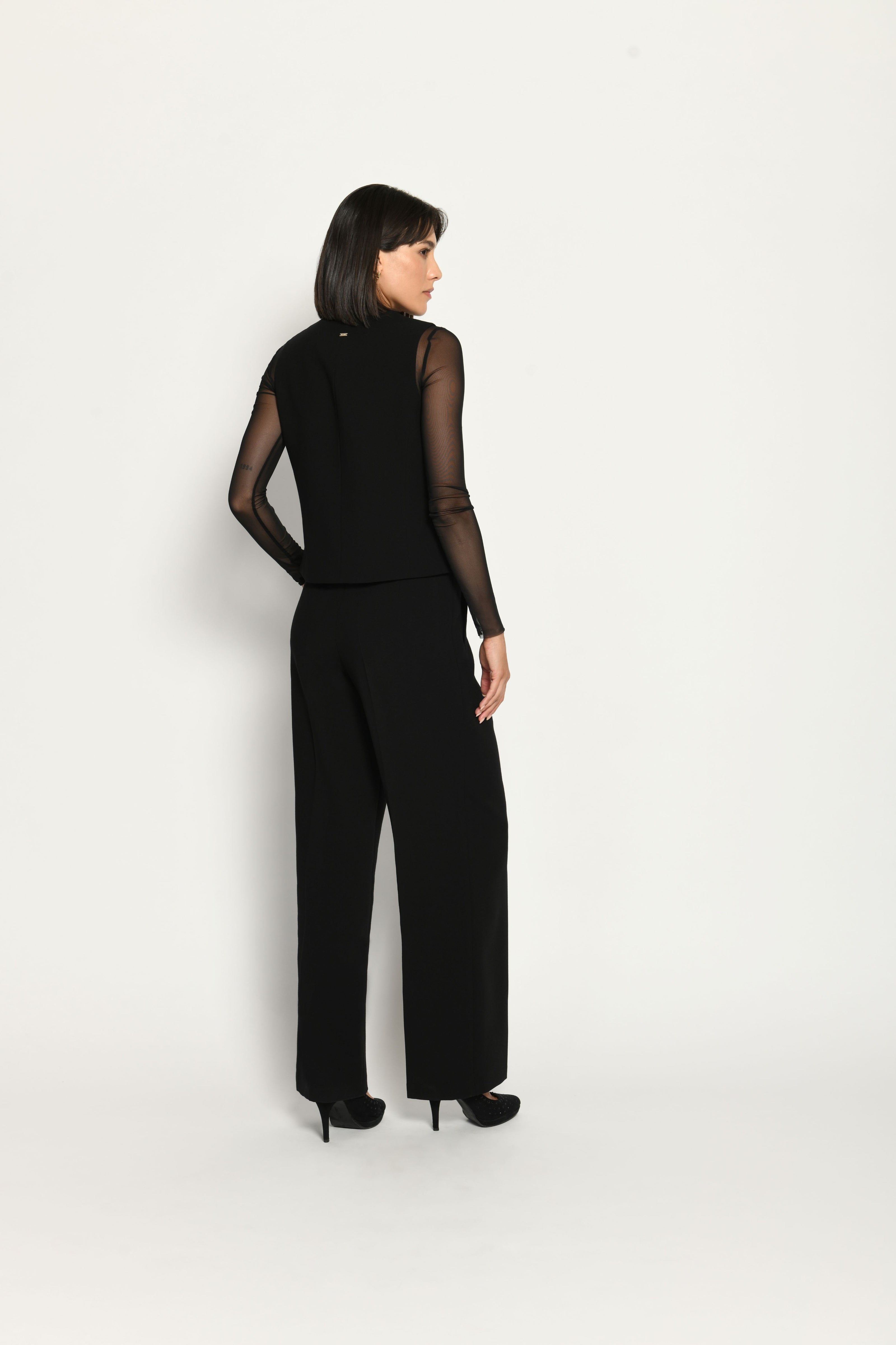 Schwarzer Slim-Fit-Hosenanzug für Damen. Model trägt Weste und lange Stoffhose – Ansicht von hinten.