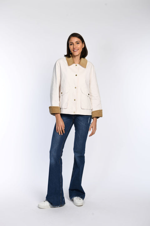 Model trägt cremfarbene Jacke mit Cord-Details an Kragen und im Ärmelsaum.