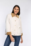 Model trägt gerade geschnittene Jacke mit Cord-Details an Kragen und Ärmeln, geschlossen durch Druckknopfverschluss.