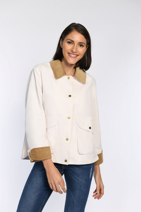 Model trägt gerade geschnittene Jacke mit Cord-Details an Kragen und Ärmeln, geschlossen durch Druckknopfverschluss.