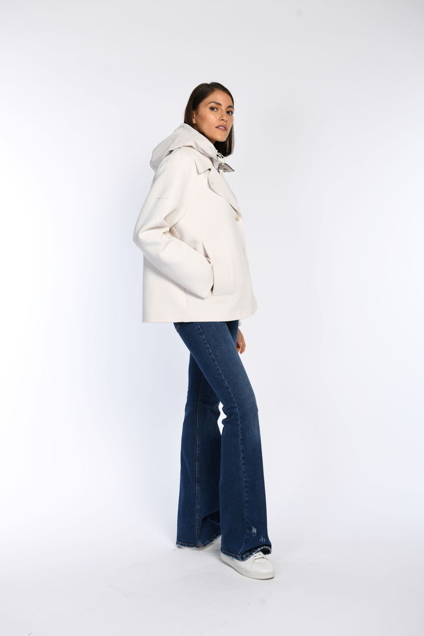 Seitenansicht einer cremefarbenen Caban-Jacke mit Kapuze an einem Model kombiniert mit einer Jeans.