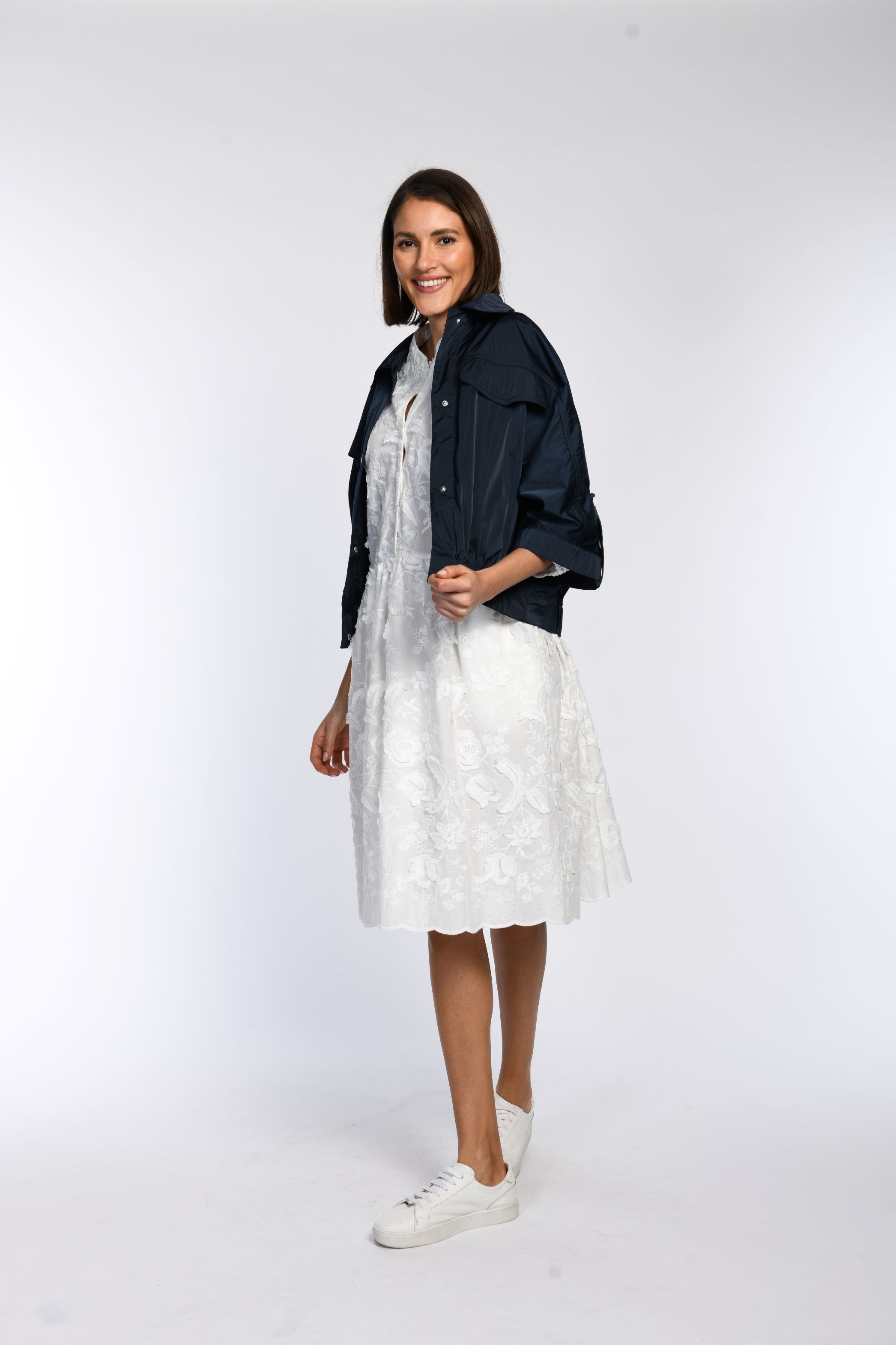 Model trägt locker geschnittene blaue Sommerjacke, offen getragen, lässig kombiniert mit weißem Kleid.