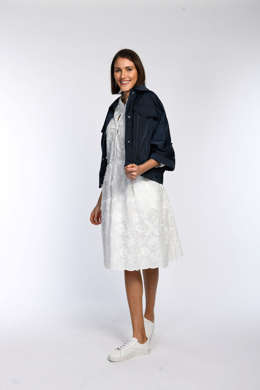 Model trägt locker geschnittene blaue Sommerjacke, offen getragen, lässig kombiniert mit weißem Kleid.