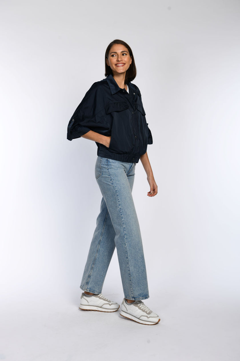 Model trägt geschlossene, blaue Sommerjacke. Durch den integrierten Gummizug im Saum entsteht ein Blouson-Effekt.