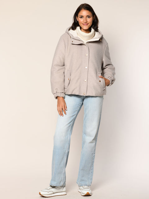Model trägt eine leger geschnittene Wolljacke mit Kapuze in der Farbe Beige- Vorderansicht.