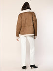 Model trägt Jacke aus Lammfellimitat in der Farbe Cognac - Rückansicht.