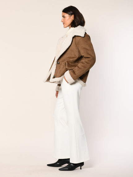Model trägt Jacke aus Lammfellimitat in der Farbe Cognac - Seitenansicht.