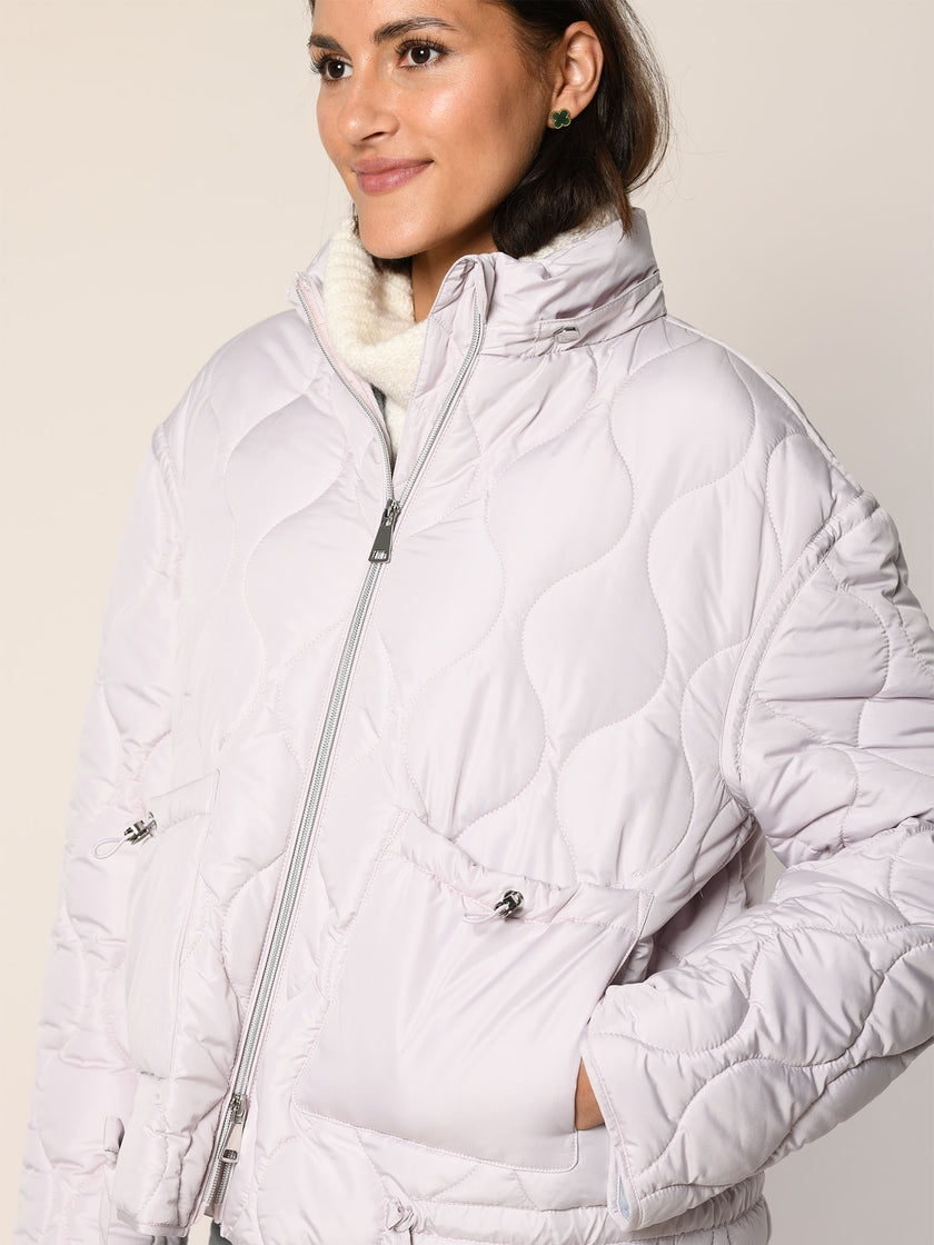 Model trägt gerade geschnittene Steppjacke mit Zwei-Wege-Reißverschluss in der Farbe Rose - Detailansicht.