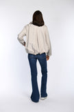 Beige Sommerjacke am Model: Rückteil mit tiefer Kellerfalte und verstellbarem Tunnelzug am Saum.