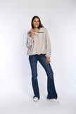 Model trägt beige, locker geschnittene Jacke mit Tunnelzug im Saum.