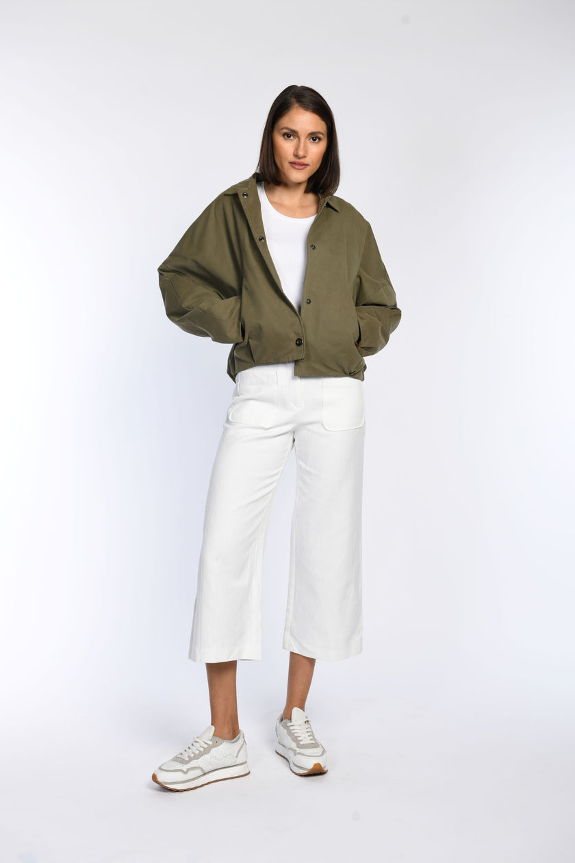 Model trägt weit geschnittene olivfarbene Jacke mit schrägen Paspeltaschen.