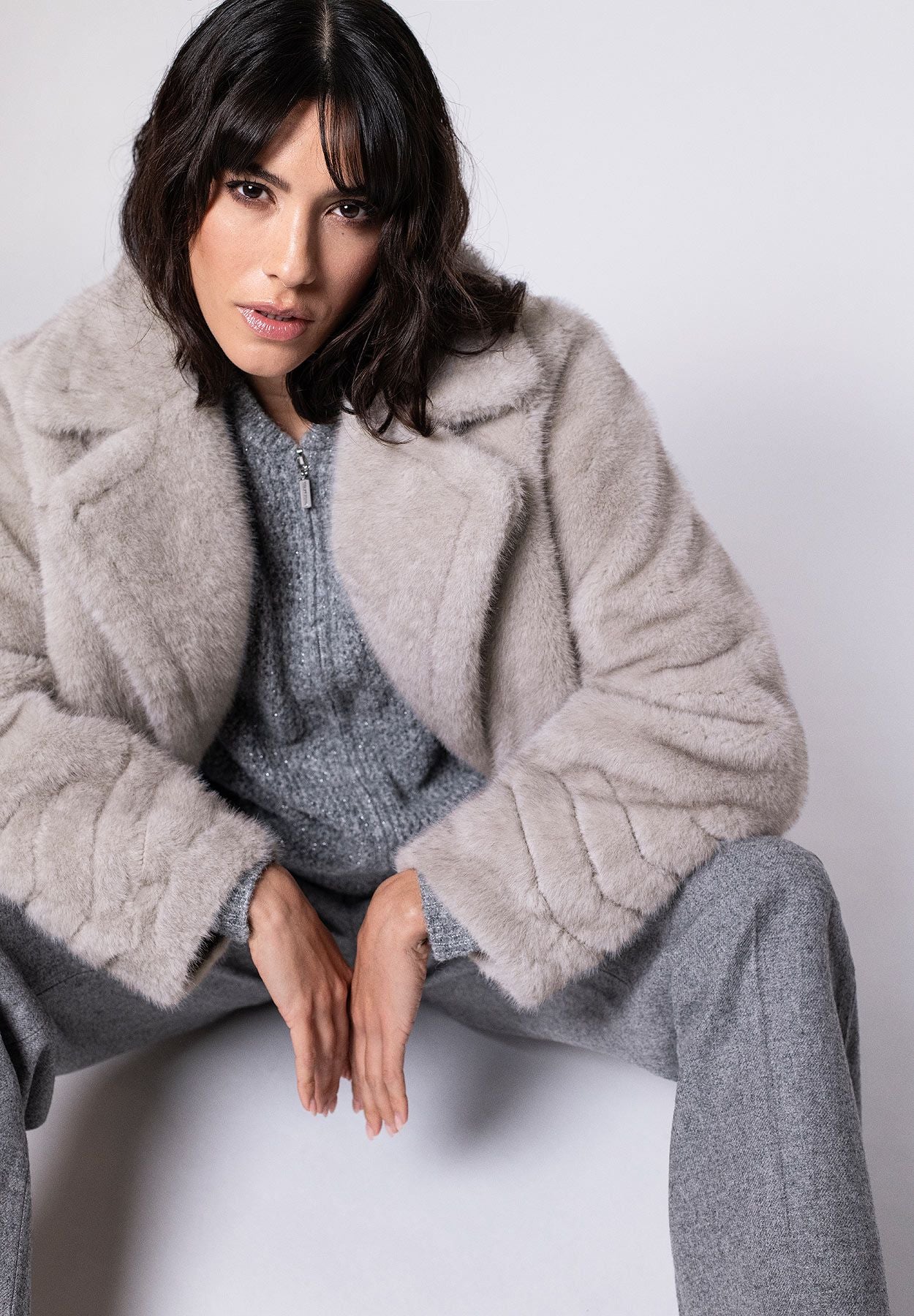 Hellgraue Jacke für Damen aus Webpelz mit Ärmelsaum in Fischgratstruktur, lässig kombiniert zur grauen Stoffhose.