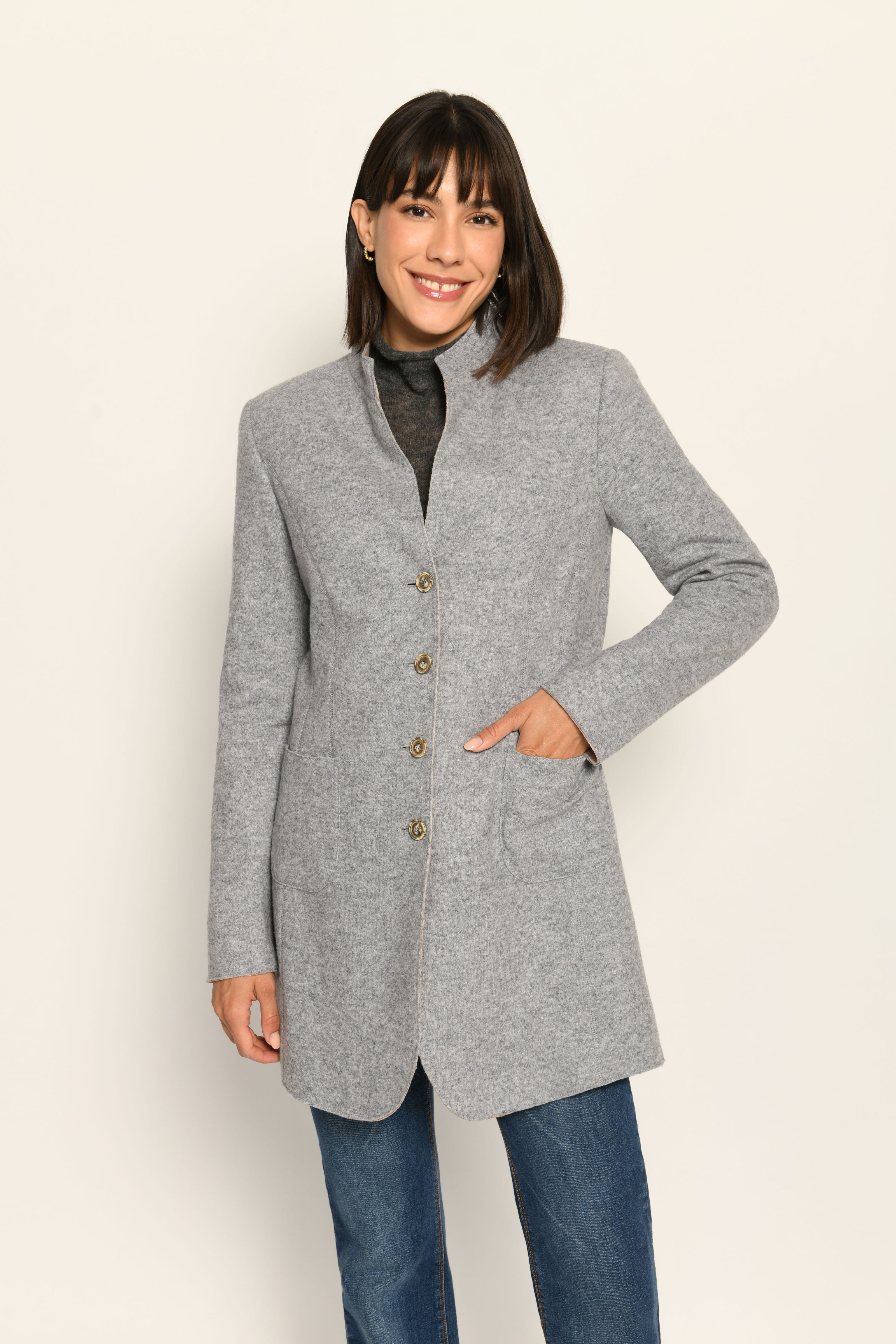 Model trägt grauen Gehrock mit geschlossener Knopfleiste und aufgestelltem Kragen – stehende Pose, Blick nach vorne
