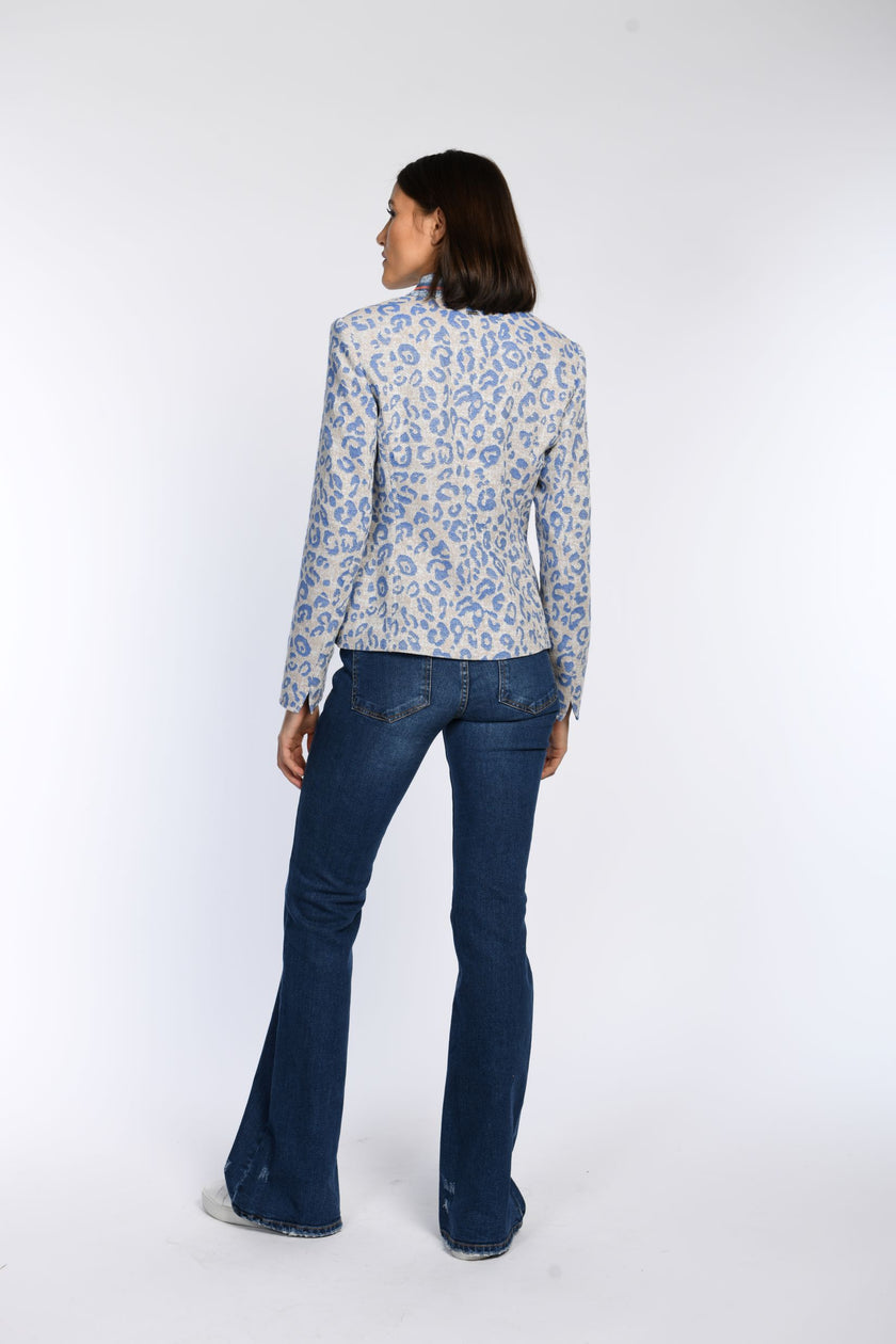 Rückenansicht des Models in einem beigen Janker mit blauem, jeansigem Leopardenprint und Ärmelschlitzen zum Umschlagen.