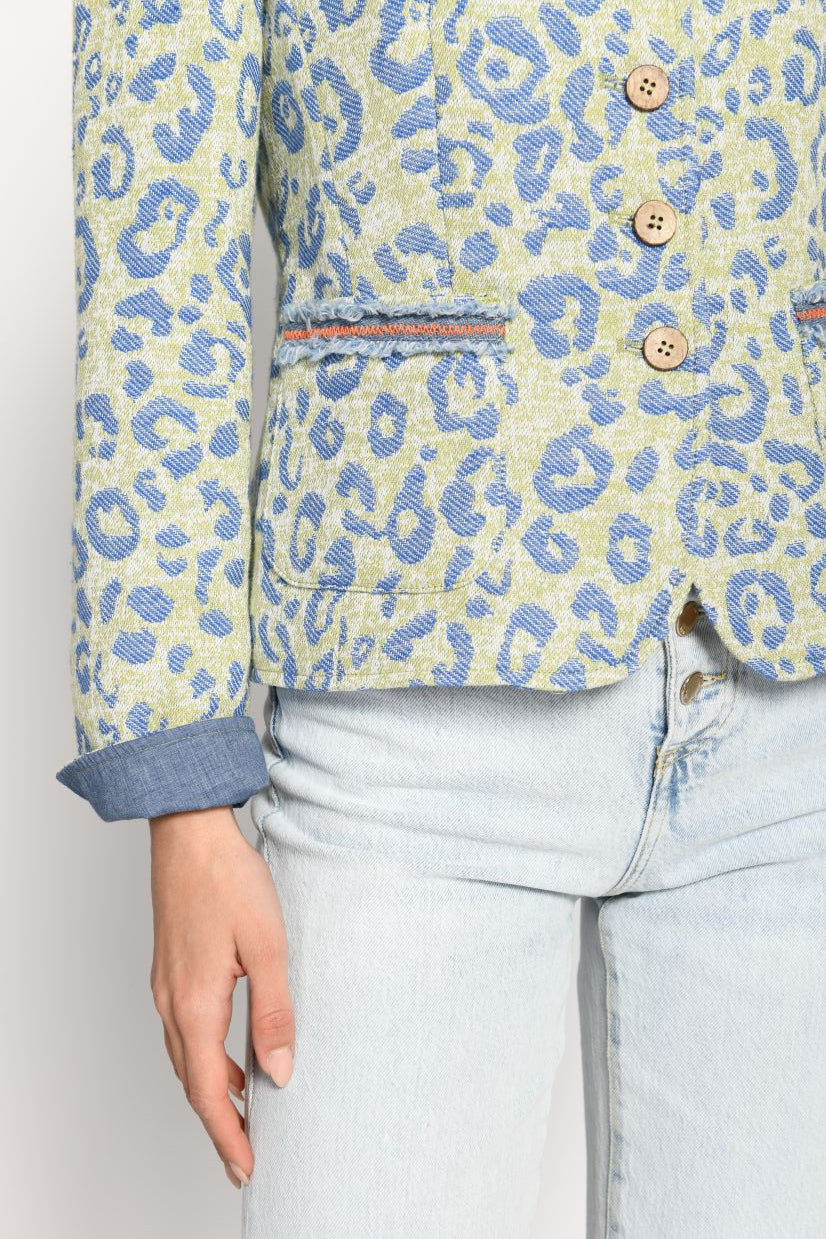 Detailaufnahme eines grünen Jankers mit jeansigem, blauem Leopardenprint und aufgesetzten Taschen mit Fransenband am Eingriff.