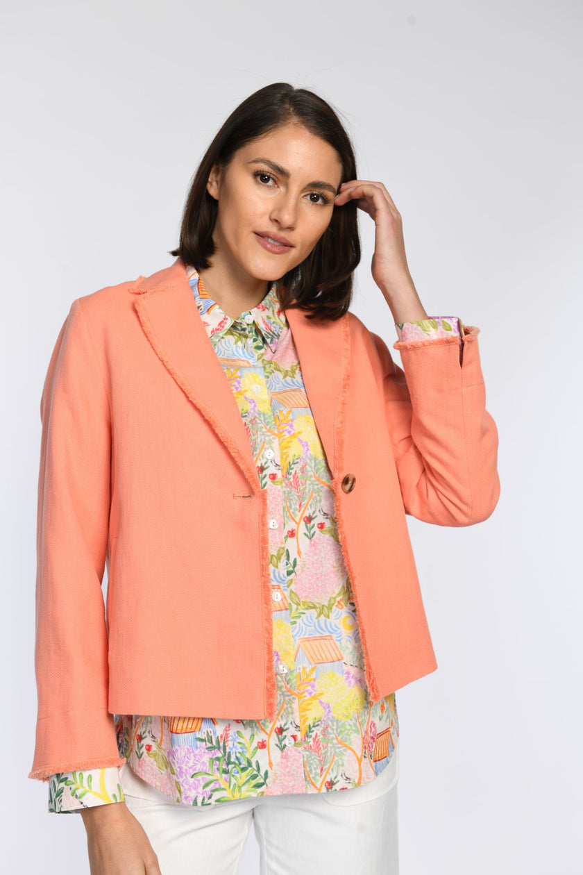 Model trägt Kastenjacke in Orange mit Fransendetails und Reverskragen.