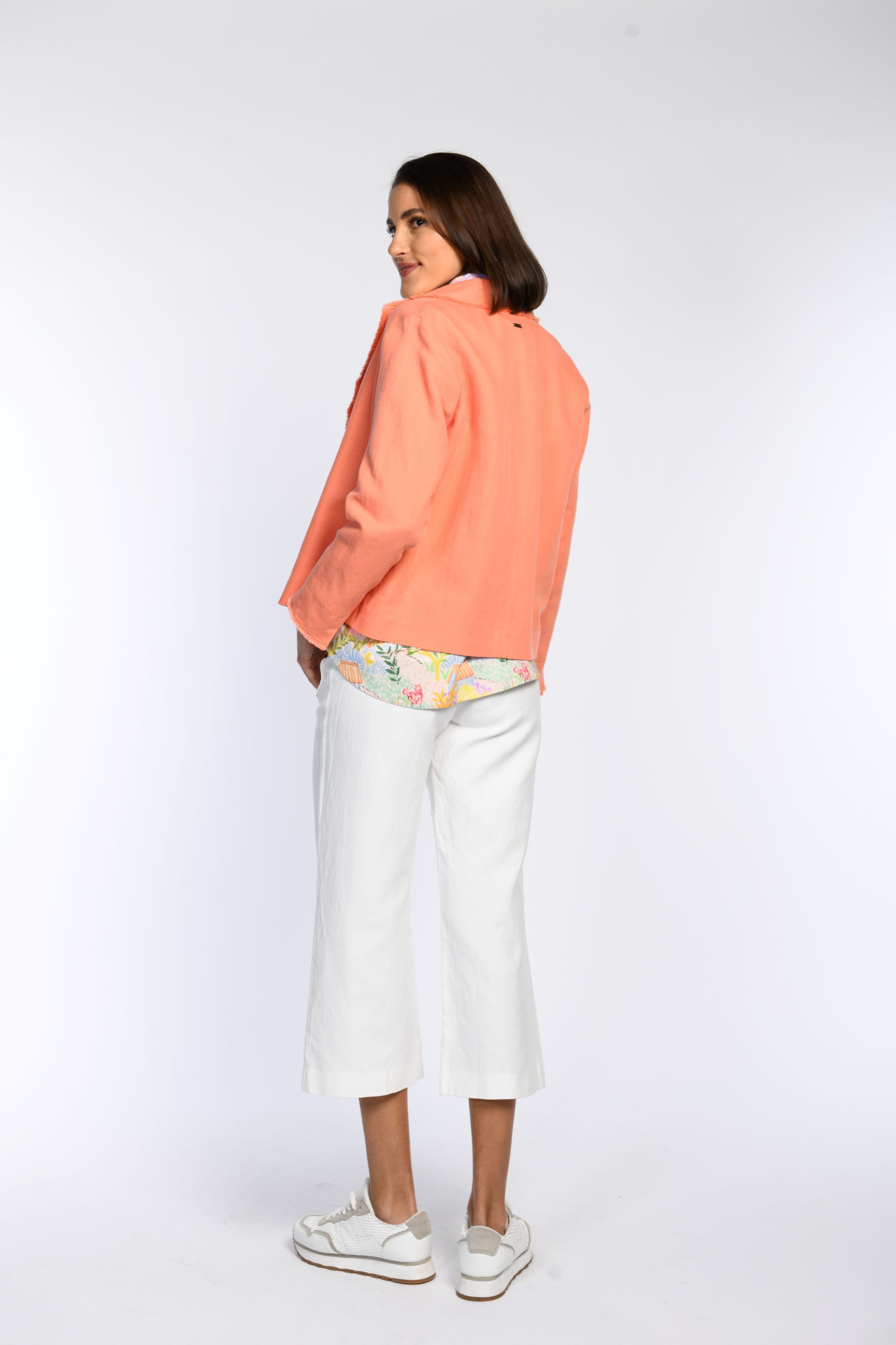 Rückenansicht: Model in kastiger, orangefarbener Jacke mit Reverskragen.