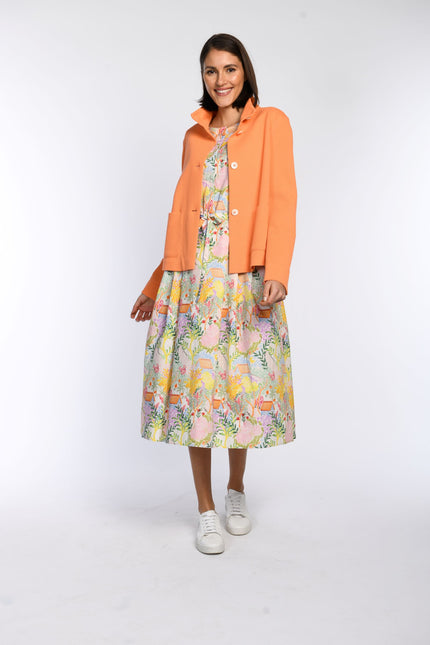 Model trägt eine orangefarbene Kastenjacke mit Stehkragen und vorderer Knopfleiste.