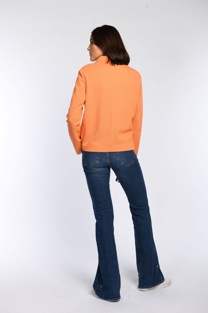 Model trägt orangefarbene Kastenjacke – Rückenansicht.