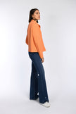 Model trägt orangefarbene Kastenjacke mit geradem Schnitt – Seitenansicht.