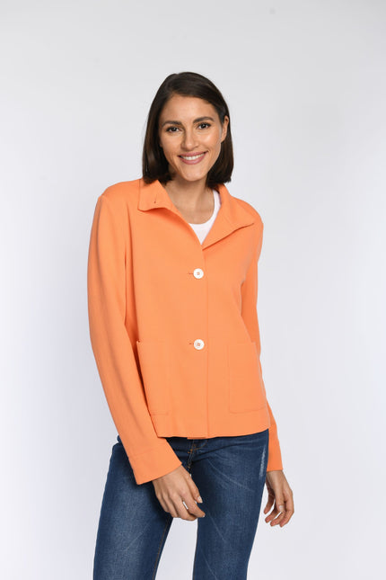 Model trägt eine geschlossene Kastenjacke in Orange mit Stehkragen und aufgesetzten Taschen.