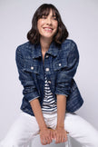 Model in gerade geschnittener Kastenjacke im Denim-Look mit Umlegekragen und Taschen auf Brusthöhe.
