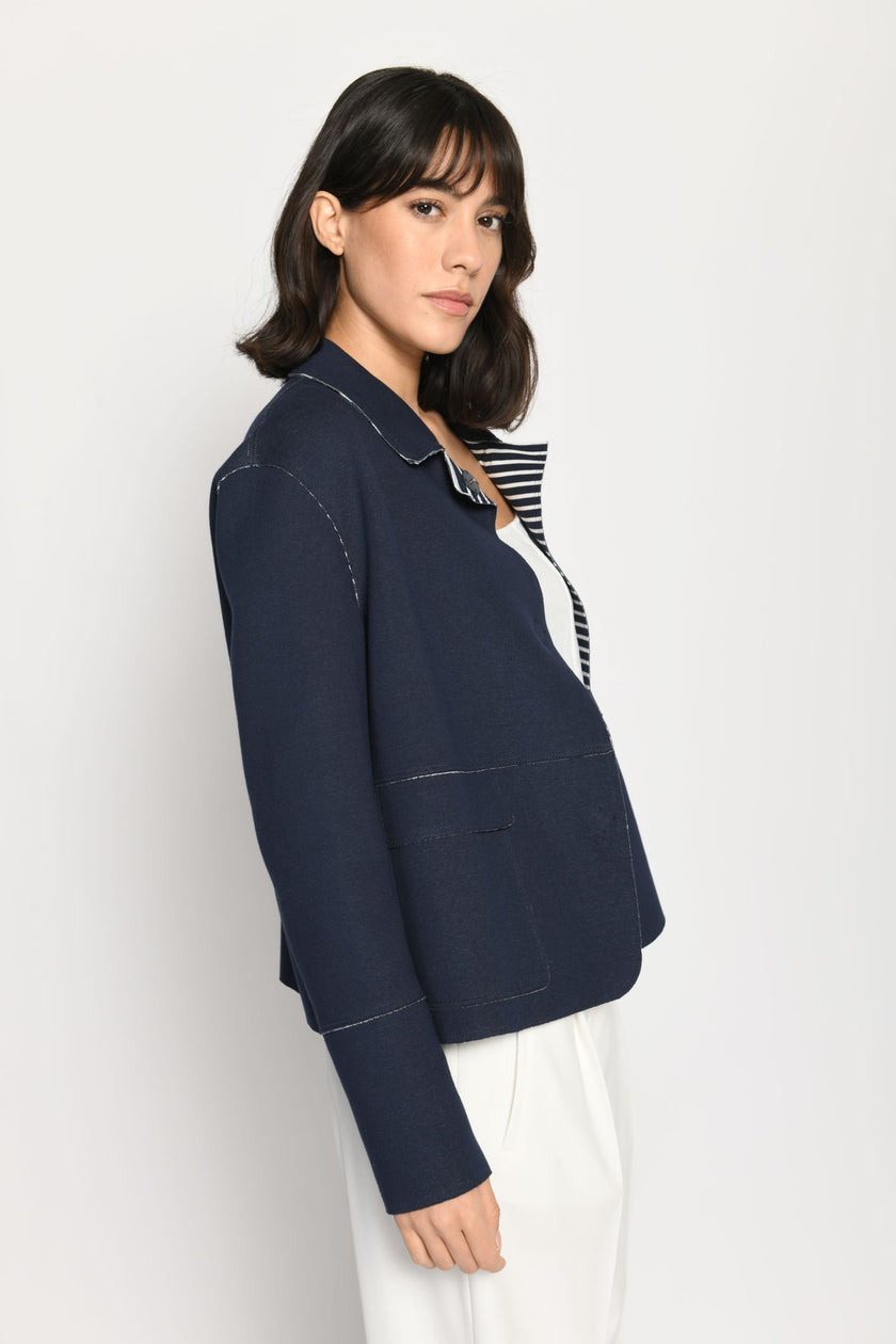 Model trägt langärmelige Kastenjacke aus Scuba, kombiniert mit weißem Top und weißer Stoffhose – Seitenansicht.